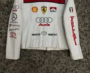 Close-up of the chest area detailing the embroidered Ferrari shield, Audi, Mercedes-Benz logos, and the distinctive red number 1.