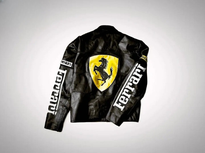 Detailed shot of the front of the black and White Ferrari Racing leather jacket showing the Vodafone and Michelin patches and the large embossed Ferrari lettering.