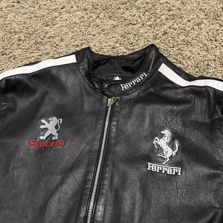 Close-up shot of the chest area showing the embroidered Ferrari and Peugeot logos on the black leather jacket.
