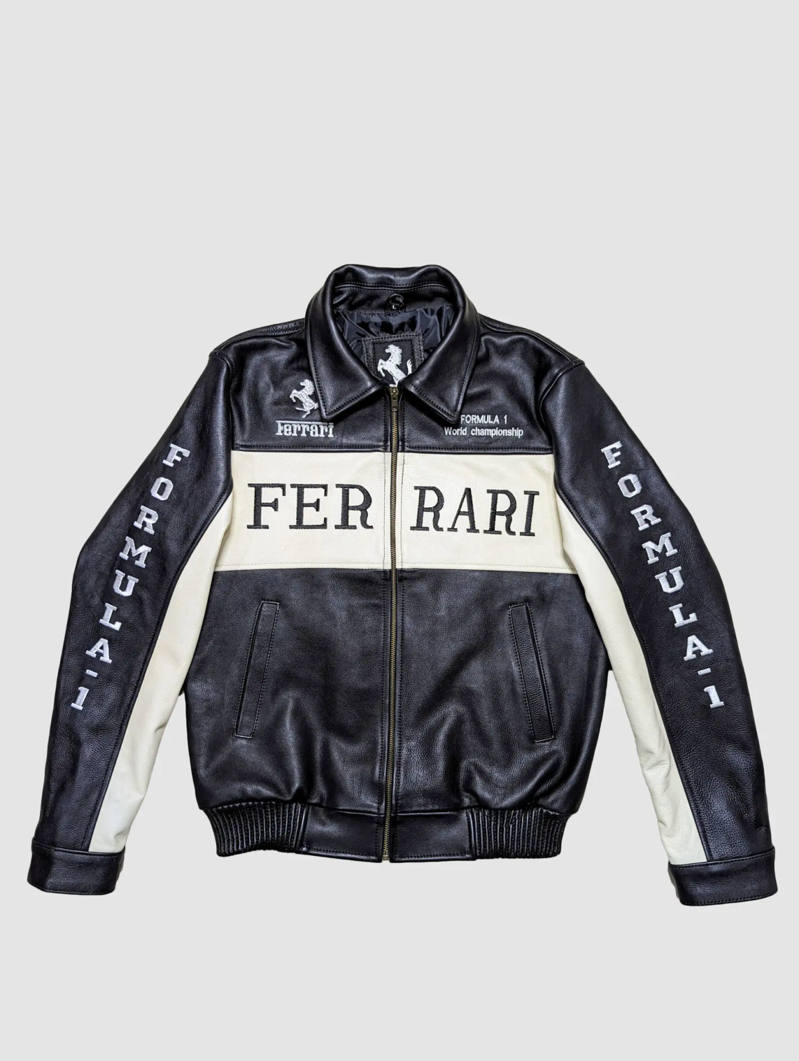Front view of a black and off-white leather Ferrari Formula 1 World Championship jacket with "FERRARI" text on the chest.