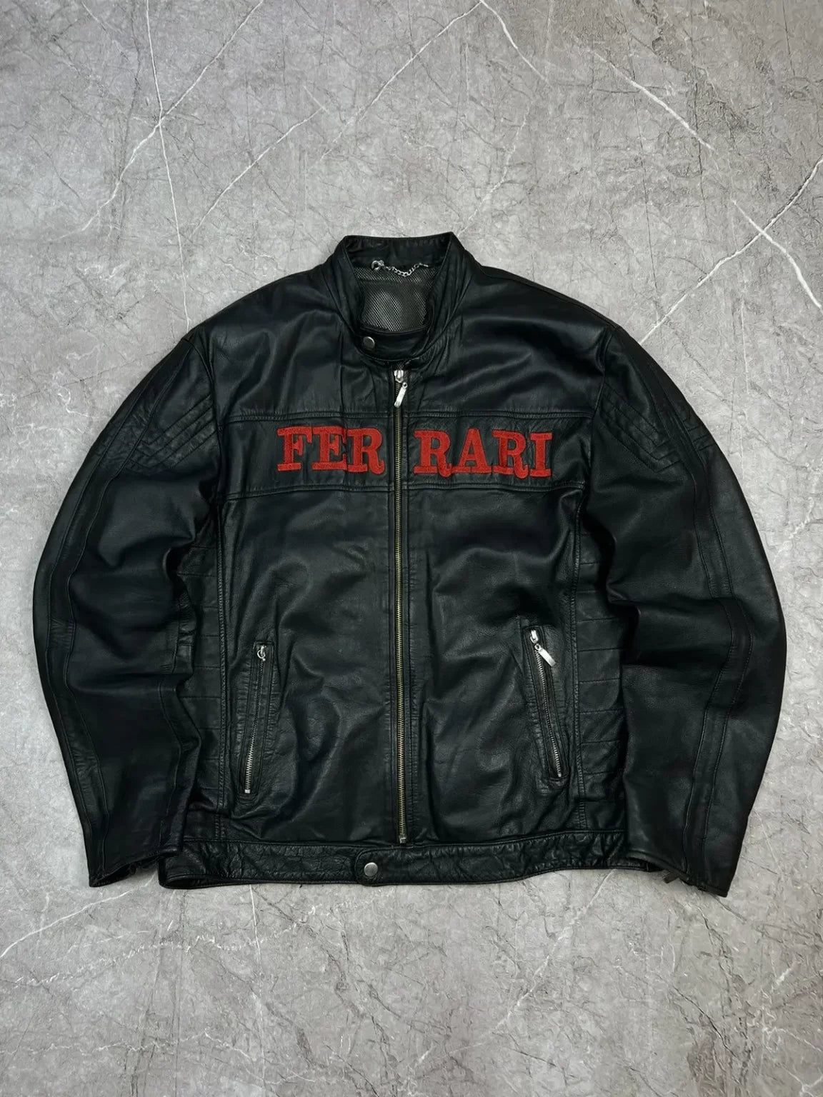 Full front view of a sleek black leather Ferrari jacket with red embroidered FERRARI text across the chest.